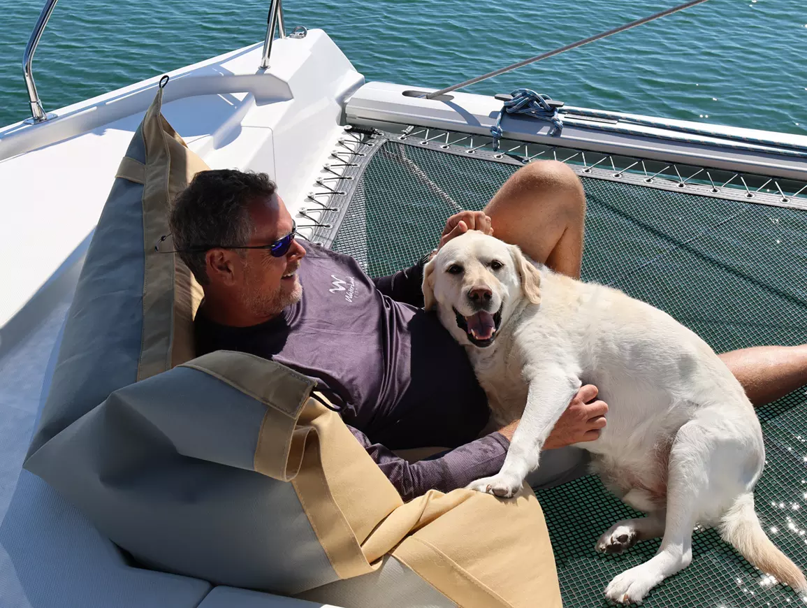 a guy with his dog on a catamaran net