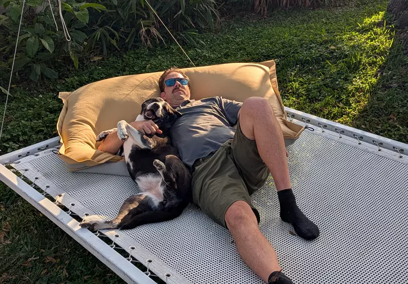 a guy and his dog on a square hole mesh daybed