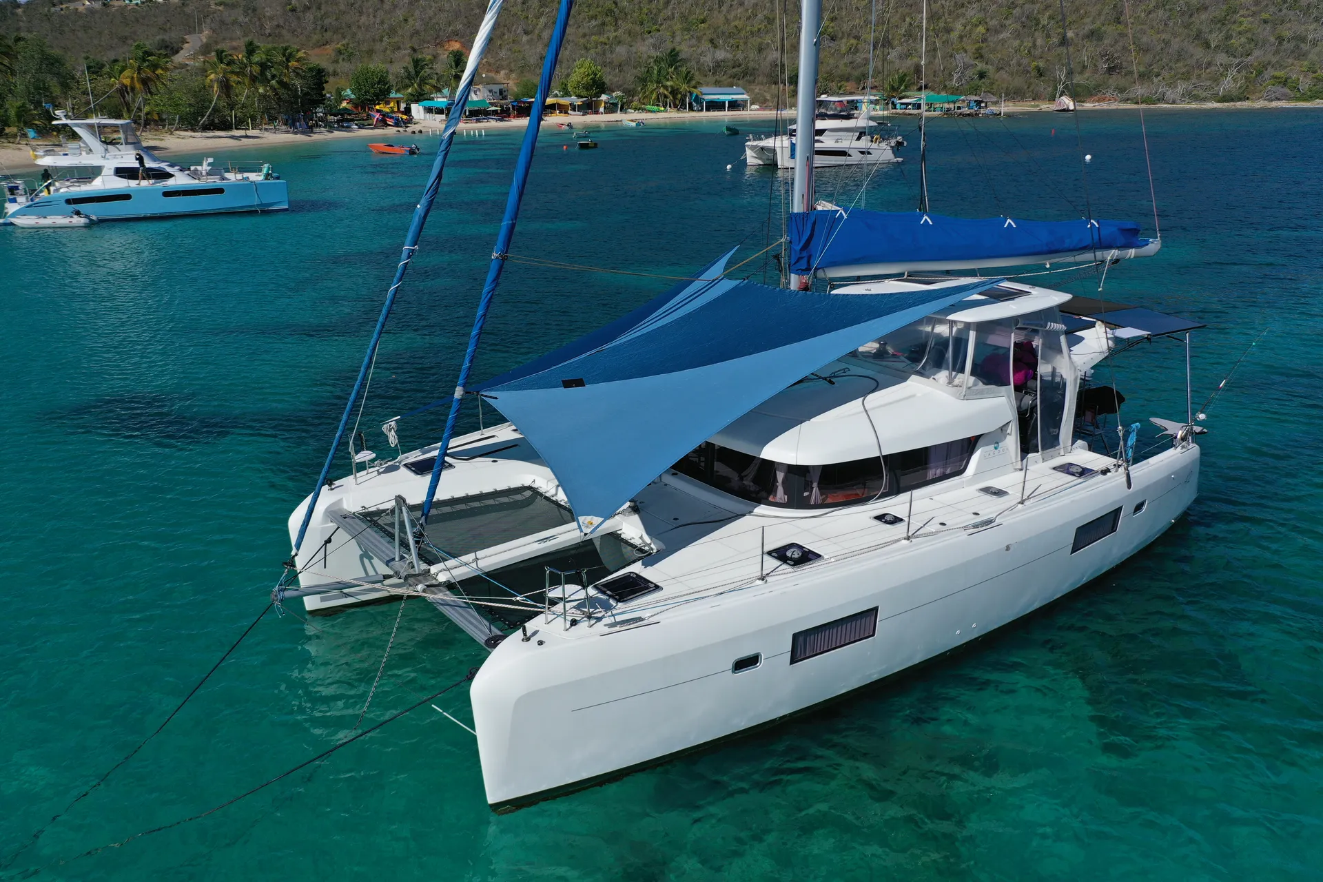 Custom multi-colored blue Sunrise SHADE rigged over the foredeck of a Lagoon 42 at anchor
